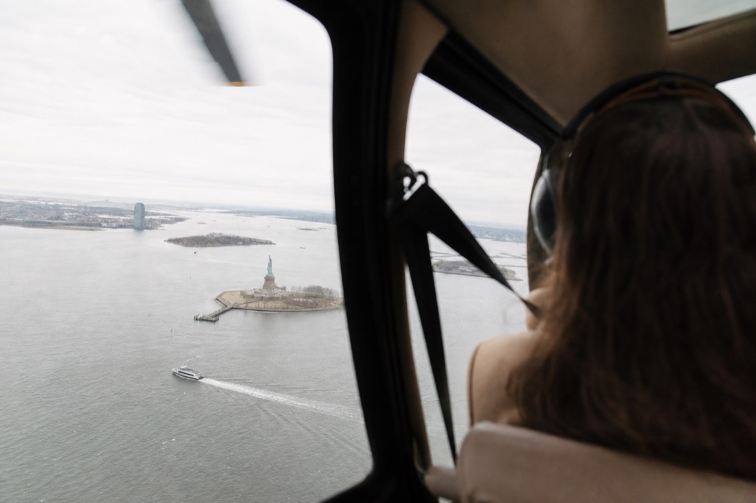 View of the Statue of Liberty and New York harbor through a helicopter window during a sightseeing flight